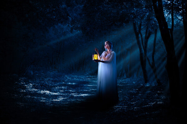 Young elven girl with lantern in night forest