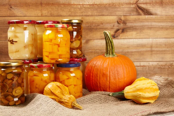 Preserved autumn vegetables on shelf in wooden wall — Stock Photo, Image