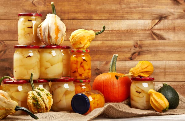 Preserved autumn vegetables on shelf in wooden wall — Stock Photo, Image