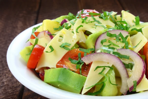 Salát s avokádem, sýrem, rajčaty a červenou cibulkou — Stock fotografie