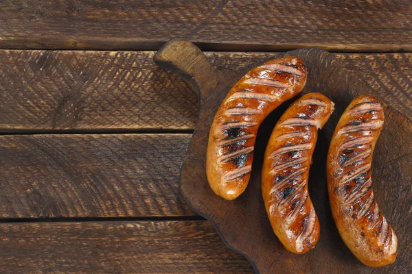 Saucisses frites sur une vieille planche de bois Images De Stock Libres De Droits