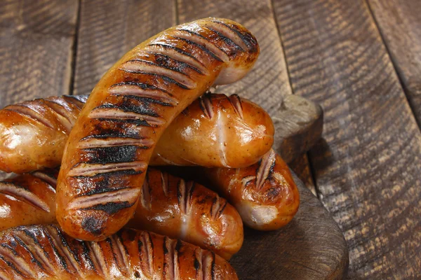 Fried sausages on old wooden board — Stock Photo, Image