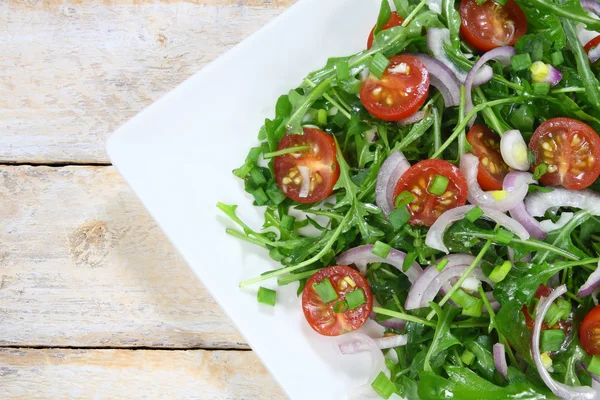 Sallad med ruccola, tomat och rödlök Royaltyfria Stockbilder