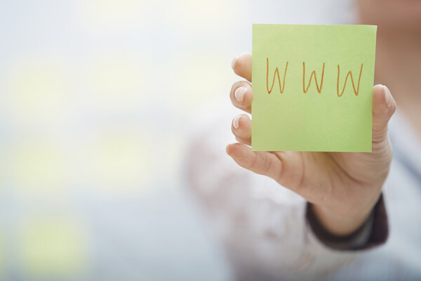 Hands holding sticky note with internet address