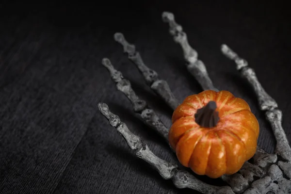 Skeleton hand holding pumpkin — Stock Photo, Image