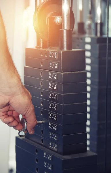 Hand av man justera vikten i träningsmaskin i gym — Stockfoto