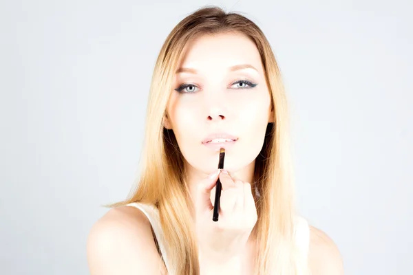Mulher loira sexy aplicando batom nos lábios. Maquiagem artista . — Fotografia de Stock