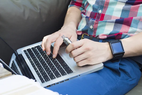 Modern insanın laptop ile izle ve e-sigara bir şey yazarak Resim kırpılmış.