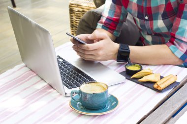 Adamın elleri bir şey açık kafede öğle yemeğinde tipik dizüstü bilgisayar ile telefon closeup. Aperatif ve kahve closeup.