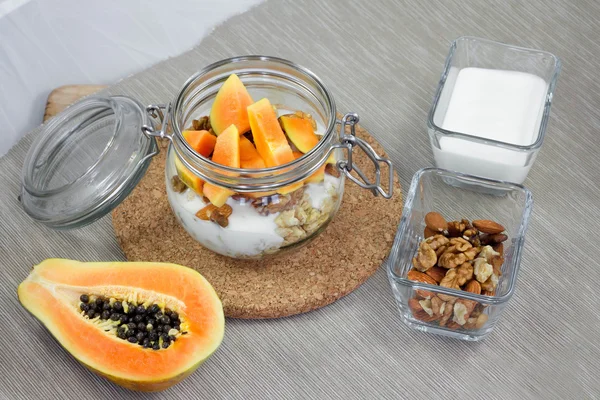 Muesli with nuts, papaya and yogurt on a napkin. Healthy breakfast