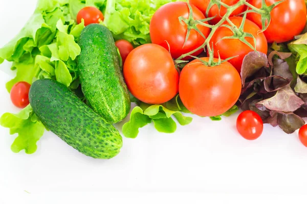 Diferentes verduras brillantes sobre un fondo blanco. Tomate, pepino y lechuga . — Foto de Stock
