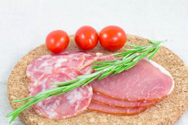 Jambon, salam biberiye ve domates kesme tahtası üzerinde.