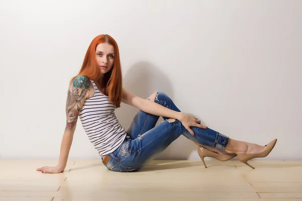 Ernstige mooie vrouw zittend op de vloer en poseren — Stockfoto