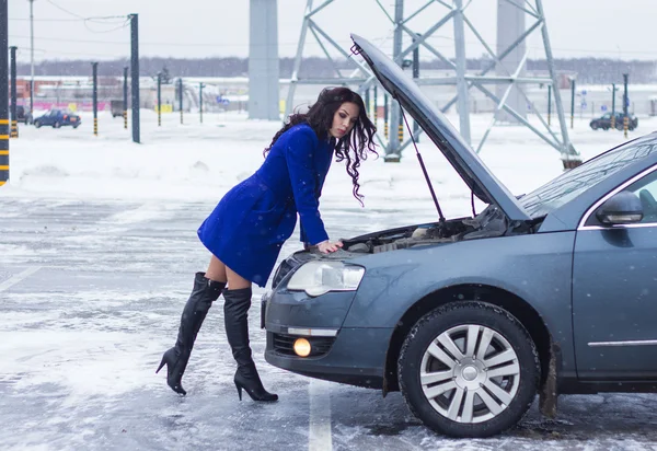 魅力的な女性を投げた彼女の脚背中と彼女の車のボンネットの下を探して — ストック写真