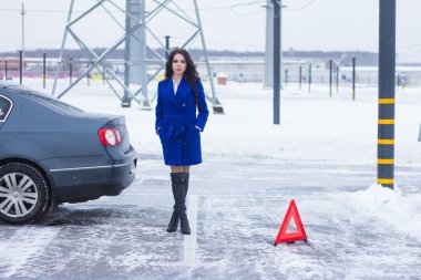 Elleri ceplerinde, acil durum işareti ayakta olan çekici kadın