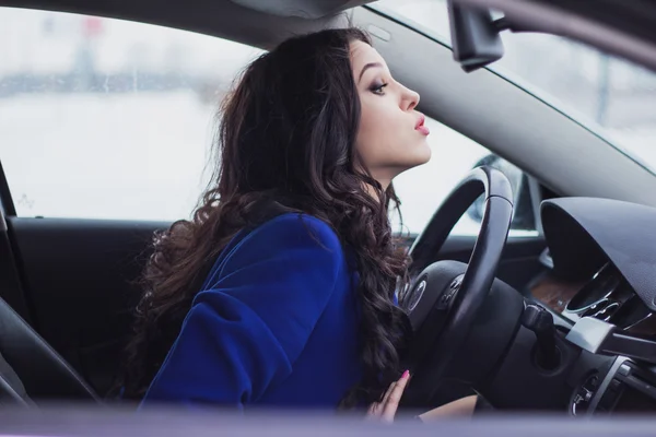 Hermosa mujer joven mirando en el parabrisas del coche — Foto de Stock