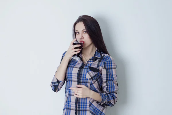 Jovem mulher olhando para a câmera e bebendo vinho tinto — Fotografia de Stock