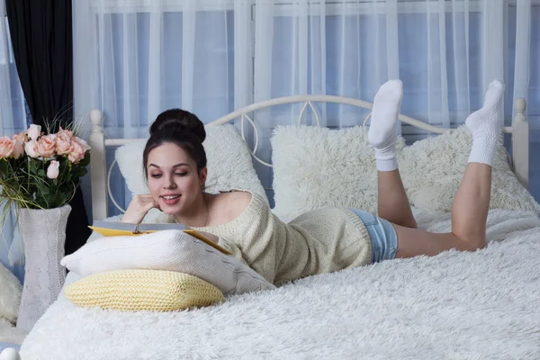 Rire fille couché sur le lit et la lecture d'un livre — Photo