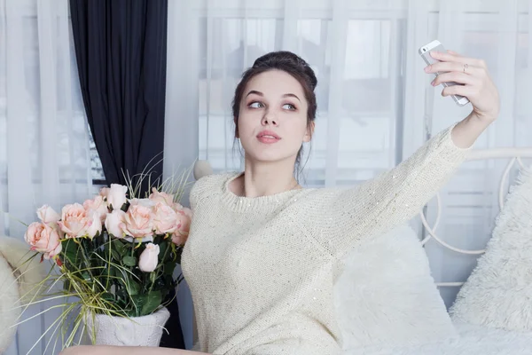 Attraktive Brünette macht Selfie mit Blumen zu Hause — Stockfoto