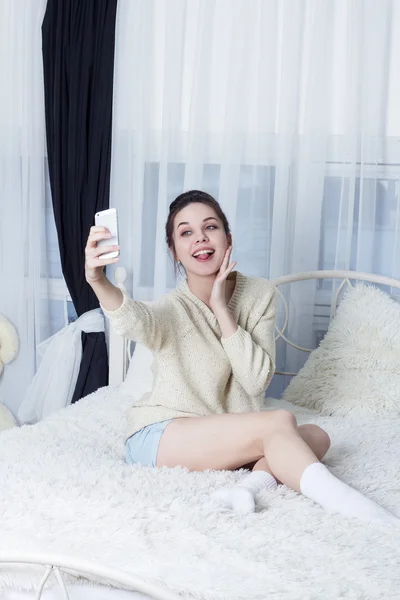 Dziewczyna się wygłupiać i pokazując język i selfie biorąc na smartphone — Zdjęcie stockowe
