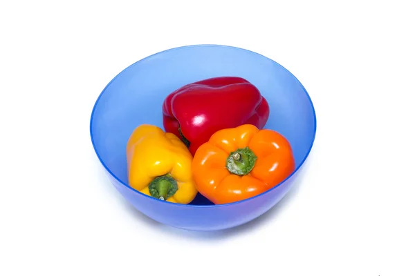 Three whole bell peppers of different colors on the board for cutting in blue bowl for food — Stock Photo, Image