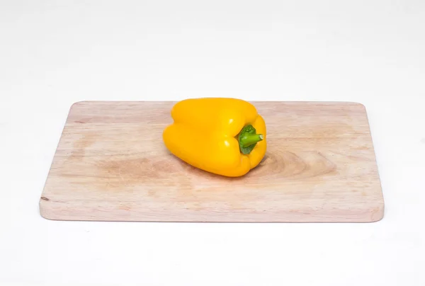 Egy egész sárga paprika, egy vágódeszka — Stock Fotó