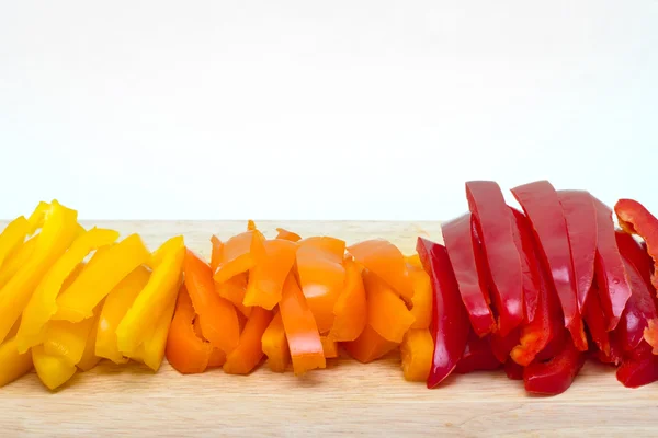 Red orange yellow peppers sliced on a cutting board — Stock Photo, Image