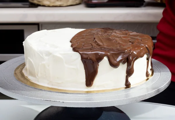 Melted chocolate spreads over cream cake — Stock Photo, Image