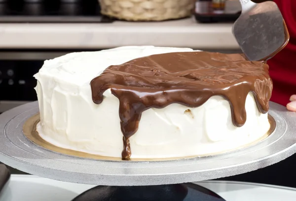 Cioccolato fuso si diffonde su torta alla panna — Foto Stock