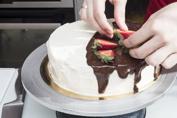 Panettiere decorare una torta con fragole — Foto Stock