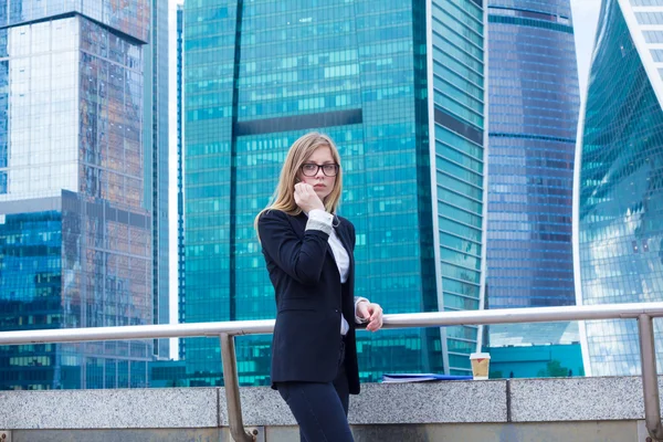 Atractiva mujer de negocios en el fondo de los rascacielos en el teléfono —  Fotos de Stock