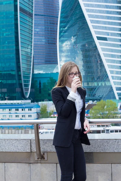 Mujer joven tomando café frente al centro de negocios —  Fotos de Stock