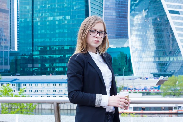 Mujer joven con café en el fondo rascacielos de negocios —  Fotos de Stock