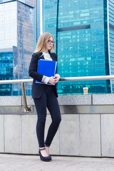 Business woman holding mapp med dokument i handen mot bakgrund av skyskrapor — Stockfoto
