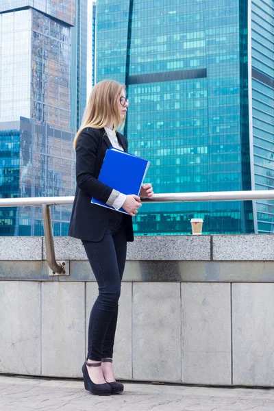 Business woman holding mapp med dokument i handen mot bakgrund av skyskrapor — Stockfoto