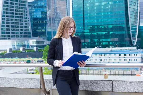 Business woman reading documents folder on the street on a background of skyscrapers — Stock Photo, Image