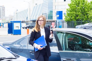 Arabasını girip Belgeler klasörüyle tutan iş kadın