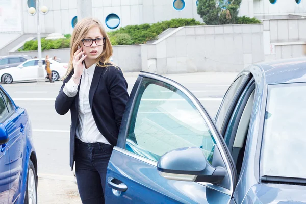 電話で話して、彼女の車の横に立っている女性 — ストック写真