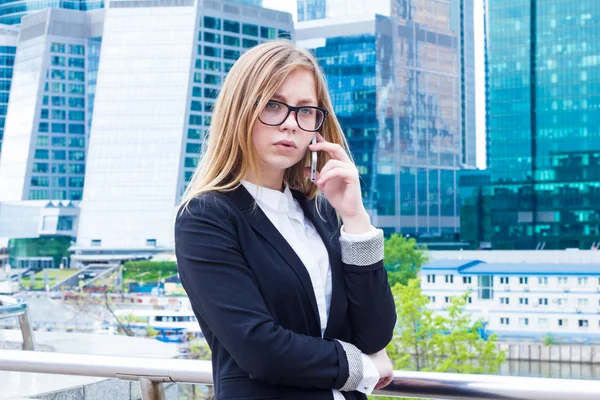 Mulher de negócios falando ao telefone no fundo de arranha-céus — Fotografia de Stock