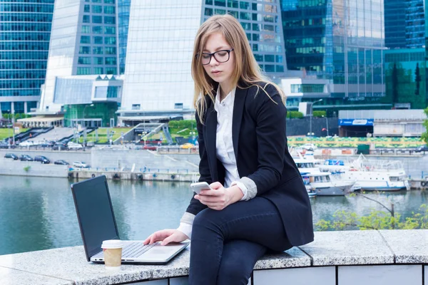 Affärskvinna på fika med en laptop och skriver ett meddelande i bakgrunden skyskrapor — Stockfoto