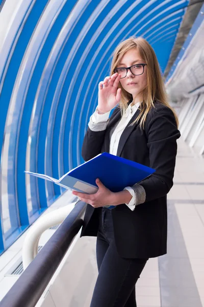 Business woman adjusts glasses and holding a folder with documents in hand — Stock Photo, Image