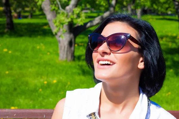 Jolie brune aux lunettes de soleil riant dans le parc par une journée ensoleillée — Photo
