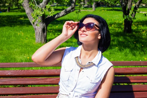 Attraktive Brünette mit Sonnenbrille lacht an einem sonnigen Tag im Park — Stockfoto