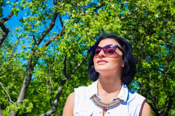Jolie brune aux lunettes de soleil reposant dans le parc — Photo
