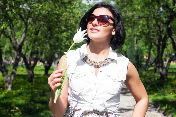 Humor de verão. Mulher com flores. Retrato de uma mulher com tulipa branca em óculos de sol — Fotografia de Stock
