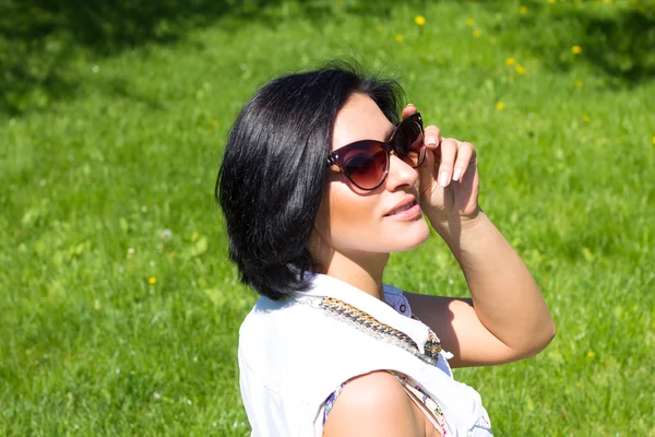 Sommerstimmung. Porträt einer Frau mit Sonnenbrille vor grünem Gras. — Stockfoto