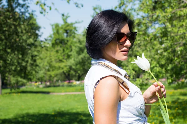 Humeur estivale. Femme avec des fleurs. Portrait d'une femme avec tulipe blanche en lunettes de soleil — Photo