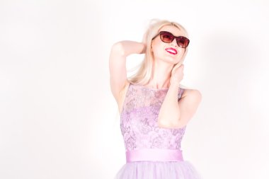 Sarı saçlı, kırmızı dudaklar ve stüdyoda güneş gözlüğü ile güzel bir kadın. Kadın gülüyor.