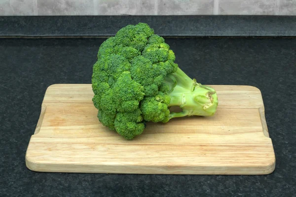 Verduras frescas verdes. Brócoli entero en una tabla de cortar — Foto de Stock