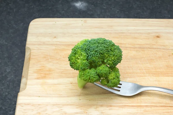 Verse groene groenten. Broccoli met een vork op een snijplank — Stockfoto